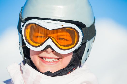 Closeup portrait of young smiling girl in helmet and ski googles at winter outdoor in the Zillertal Arena, Austria