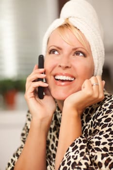 Attractive Smiling Caucasian Woman Talking on Her Cell Phone with a Towel on Her Head.