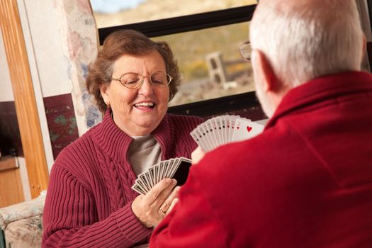 Happy Senior Adult Couple Playing Cards in Their Travel Trailer RV.