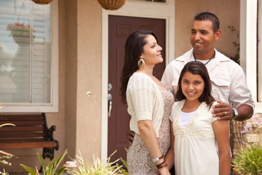 Happy Hispanic Mother, Father and Daughter in Front of Their Home.