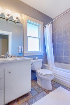 Blue bathroom with white cabinets with stone tiles and blue tiles.