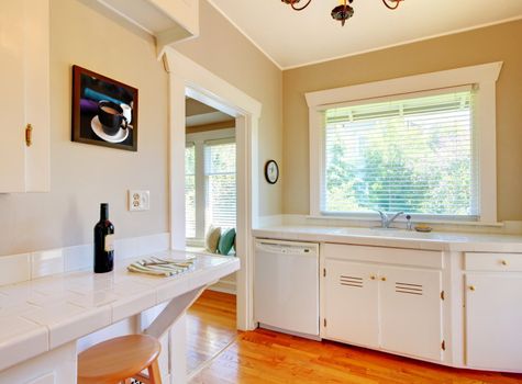 White kitchen with cherry hardwood floor, sink and window.