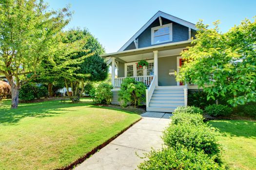 Grey small old American house front exterior with white staircase during summer.