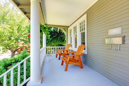 Front porch with chairs and columns of old craftsman style home.