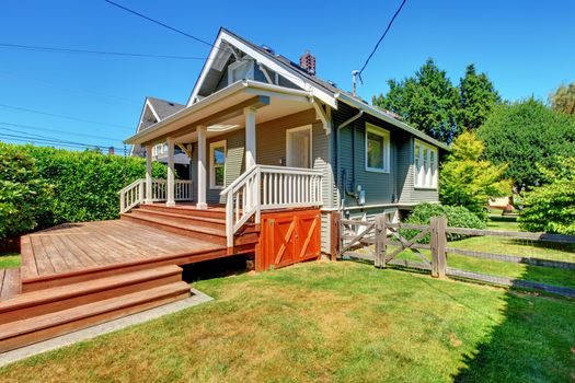 Small grey house with back large porch and old fence.