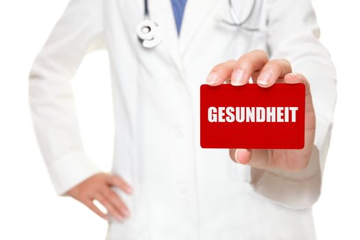 Doctor holding GESUNDHEIT card written health in German. Cropped view image with selective focus to the card.