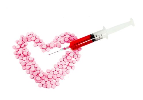 Syringe and pink pills form heart shape isolated on white background