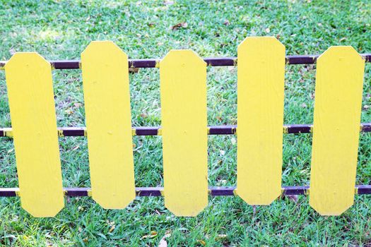 yellow wooden fence on a green meadow