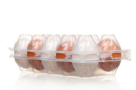 Brown and white eggs in the plastic box over white background