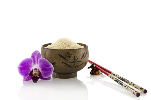 wooden cup of rice with orchid and chopsticks isolated on white