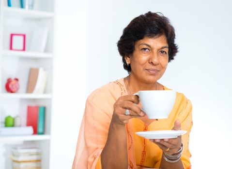 Mature Indian woman drinking coffee / tea at home