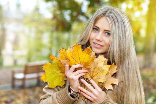 Young woman holding leaves in a park in autumn