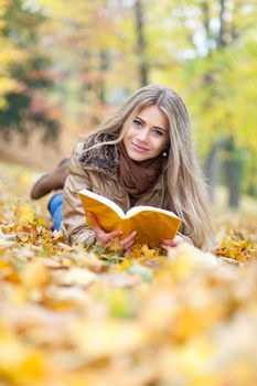 Beautiful woman in a park, reading and smiling