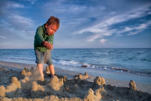boy at the sea builds sand castles
