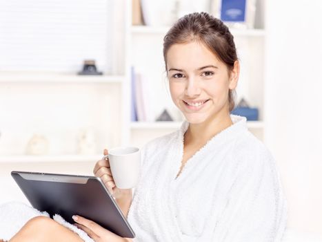 girl in bathrobe at home with touch pad computer and drink