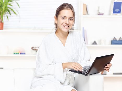 Woman in bathrobe at home with computer