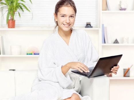 Woman in bathrobe at home with computer