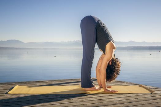 An image of a pretty woman doing yoga at the lake