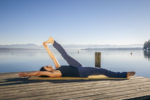 An image of a pretty woman doing yoga at the lake