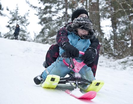 Two young boys going downhill on a modern snow sledge