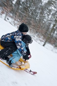 Two young boys going downhills on a modern snow sledge