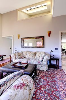 Living room with high ceiling with red rug and sofas.