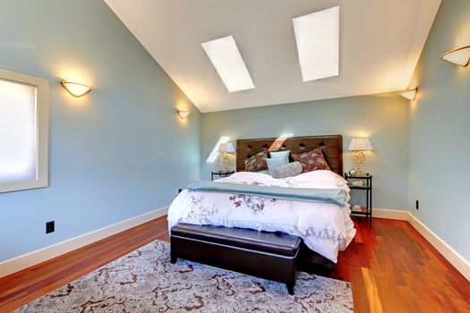 Blue bedroom with bed and skylight and cherry hardwood.