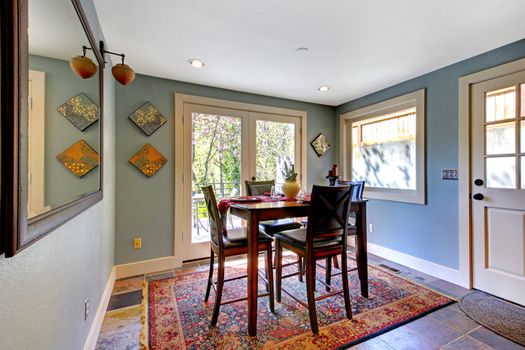 Blue bright dining room with red rug and high table.