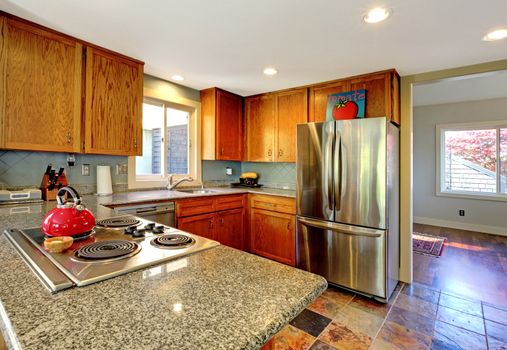 Kitchen with granite countertop stove and red tea pot.