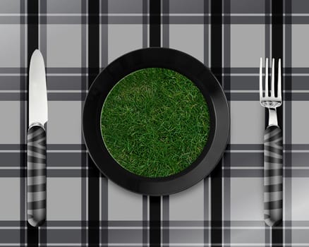 green grass on black plate with knife and fork.