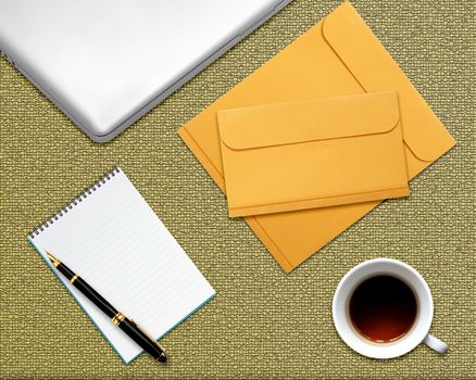 business desktop with laptop, notepad, envelops and coffee