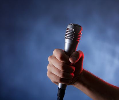 microphone in hand on the dark background