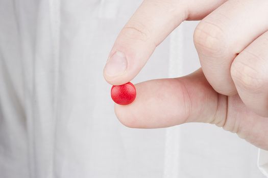 Close-up photograph of a hand holding a red tablet.