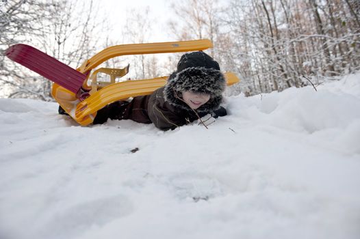 Young boy doing an overturn with a snow sledge