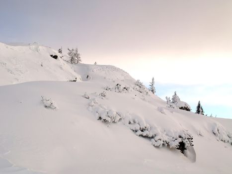 Mountain top covered with snow at sunset.