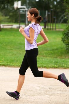 Young and attractive sporty girl running in the park