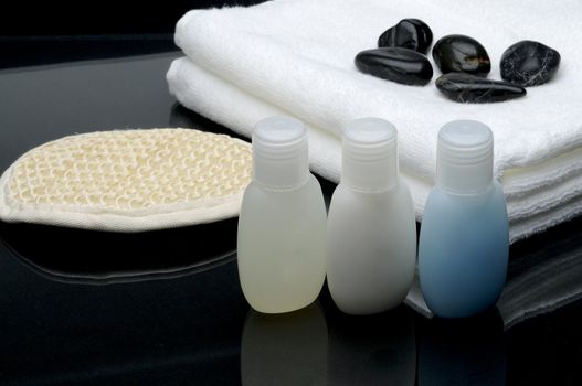 Spa setting, shampoo, towel, stones and bath glove