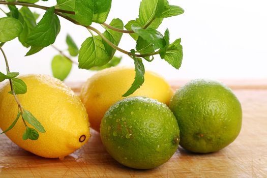 Green lime, yellow lemon and fresh mint on wooden surface