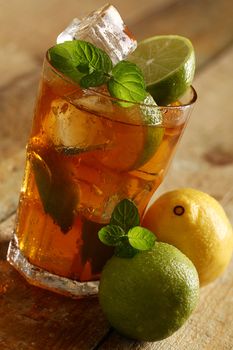 Fresh cold tea with lime, mint and lemon on a wooden surface