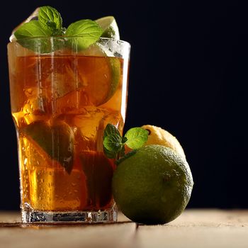 Fresh cold tea with lime, mint and lemon on a wooden surface