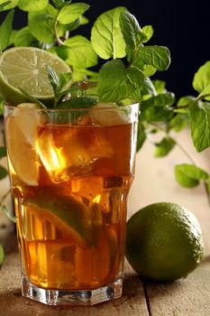 Fresh cold tea with lime, mint and lemon on a wooden surface