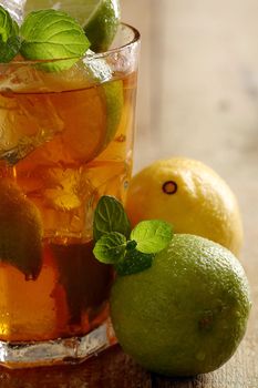 Fresh cold tea with lime, mint and lemon on a wooden surface