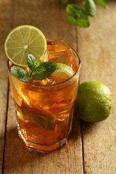 Fresh cold tea with lime, mint and lemon on a wooden surface