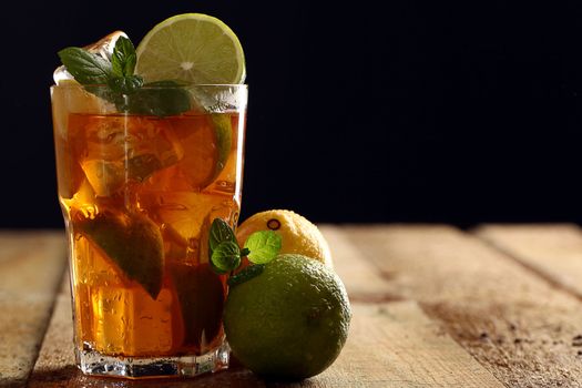 Fresh cold tea with lime, mint and lemon on a wooden surface