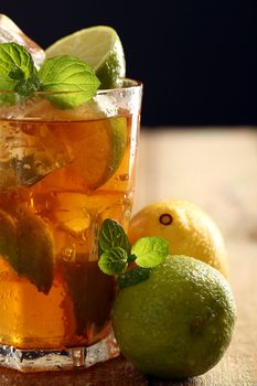 Fresh cold tea with lime, mint and lemon on a wooden surface