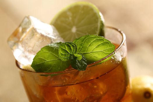 Fresh cold tea with lime, mint and lemon on a wooden surface