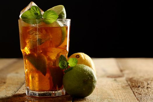 Fresh cold tea with lime, mint and lemon on a wooden surface