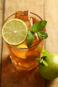 Fresh cold tea with lime, mint and lemon on a wooden surface