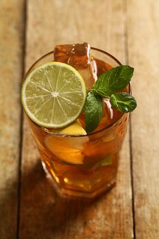 Fresh cold tea with lime, mint and lemon on a wooden surface