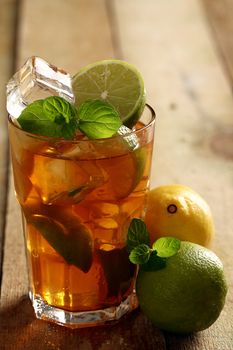 Fresh cold tea with lime, mint and lemon on a wooden surface